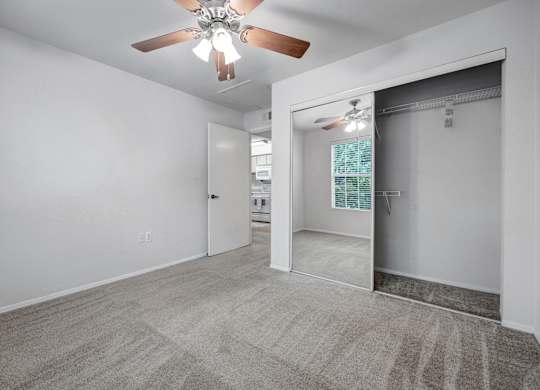 A room with a ceiling fan and carpeted floor.