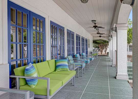 A long row of green couches are lined up on a patio.