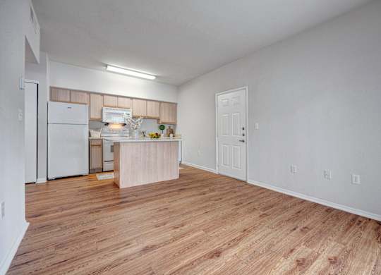 A kitchen with white appliances and wooden floors.