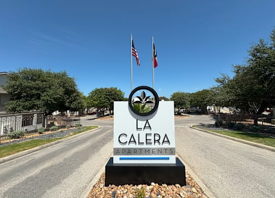 A sign for La Calera Apartments stands in front of a road.