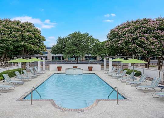 A pool surrounded by lounge chairs and umbrellas.