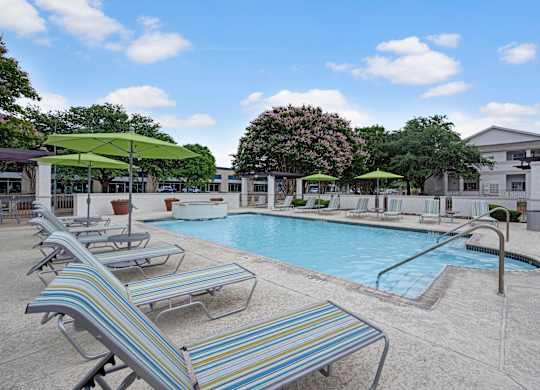 A pool with sun loungers and umbrellas.