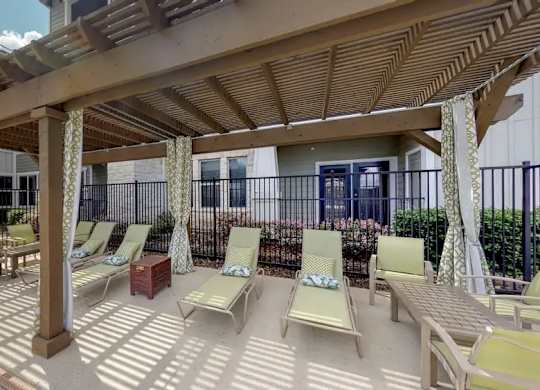 A sunny day at the outdoor seating area with wooden pergola and lounge chairs.
