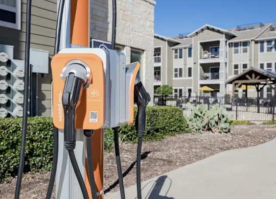 A row of electric vehicle charging stations are installed outside apartment buildings.