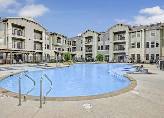 A large swimming pool in front of apartment buildings.