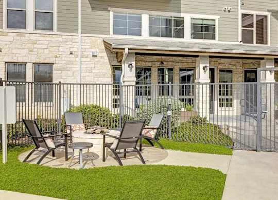 A patio with chairs and a table is in front of a house.