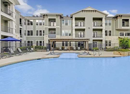 A large swimming pool in front of apartment buildings.