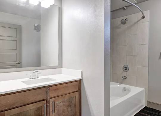 A white sink with a wooden cabinet in a bathroom.