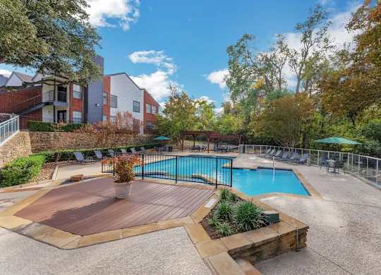 A pool surrounded by a deck and trees.