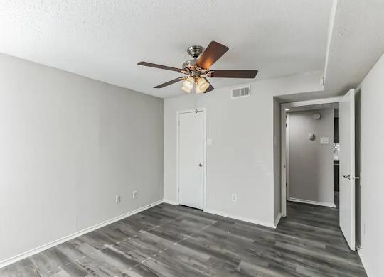 A room with a ceiling fan and a door.