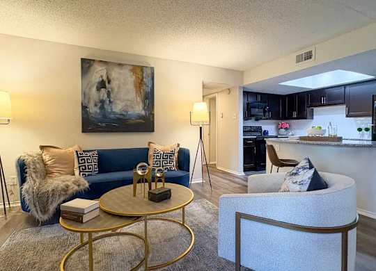 A living room with a blue couch and a painting on the wall.