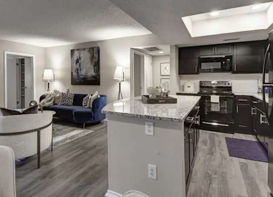 A modern kitchen with a black refrigerator and a dining table with chairs.