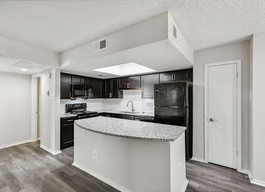 A kitchen with a black refrigerator and a white island.