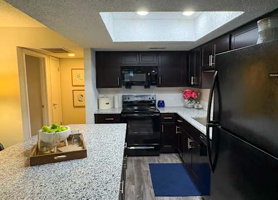 A black refrigerator is on the right side of a kitchen.