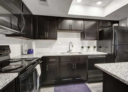 A kitchen with black cabinets and a white countertop.