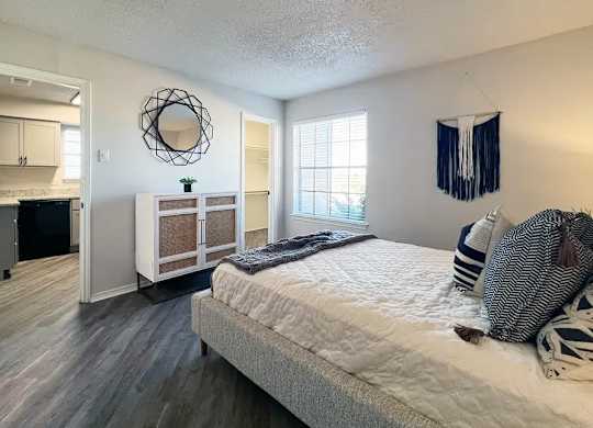 A bedroom with a bed, a window, and a mirror.