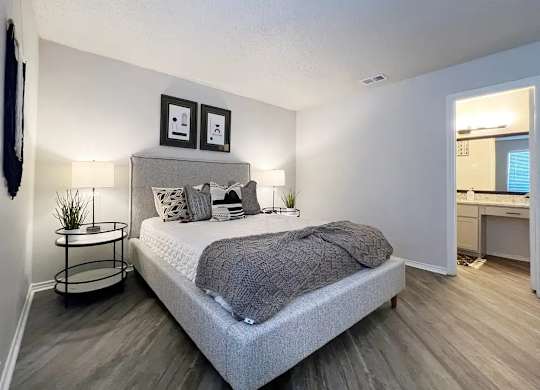 A bedroom with a bed, nightstand, and two framed pictures on the wall.