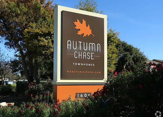 A sign for Autumn Chase Townhomes with a leaf logo and website.
