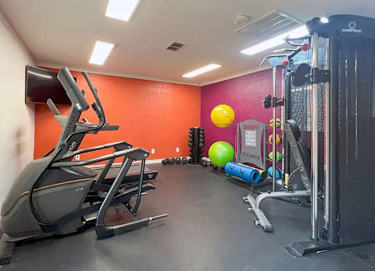 A gym with a treadmill, exercise balls, and dumbbells.