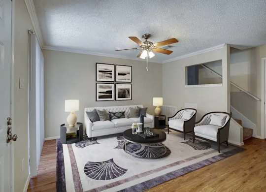 A living room with a white couch, two chairs, a coffee table, and pictures on the wall.