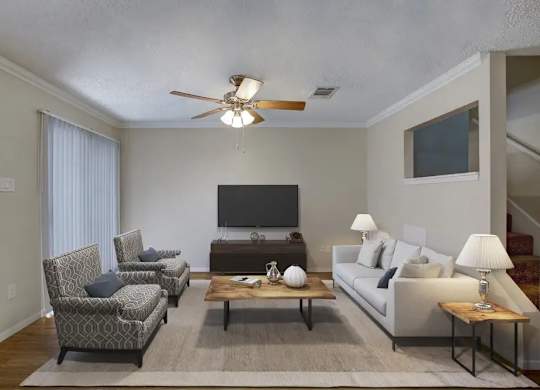 A living room with a television, two chairs, a couch, and a coffee table.