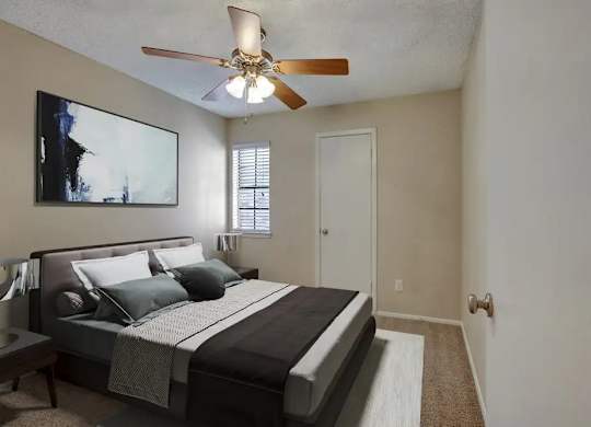 A bedroom with a large bed and a ceiling fan.