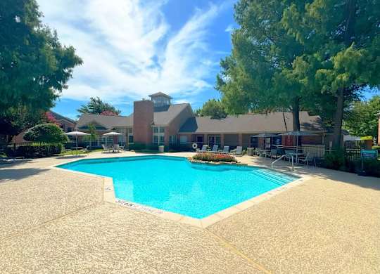 A large swimming pool in front of a building surrounded by trees.
