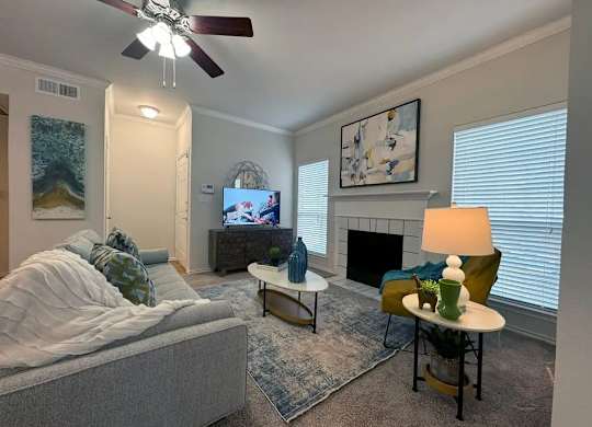 A living room with a grey couch, a coffee table, a fireplace, and a painting on the wall.