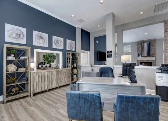 A modern office space with blue chairs and a grey desk.