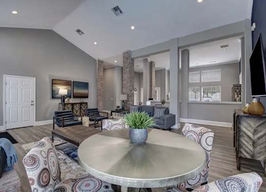 A modern living room with a glass table and patterned couches.