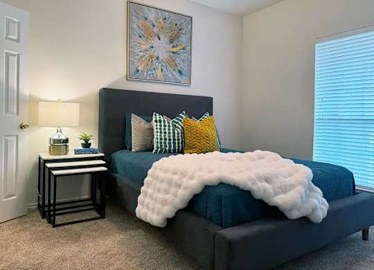A bedroom with a bed covered in a white fluffy blanket and a blue bedspread.