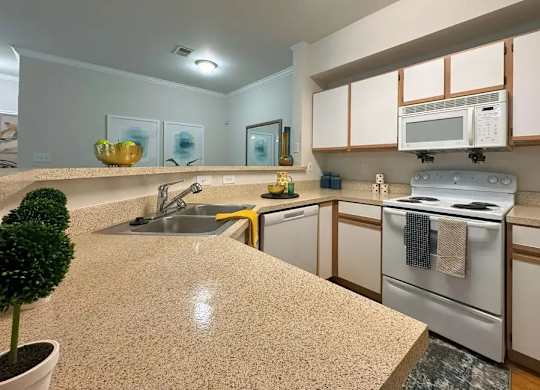 A kitchen with a countertop, sink, and stove.