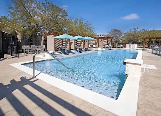 A large outdoor swimming pool with a slide and sun shades.