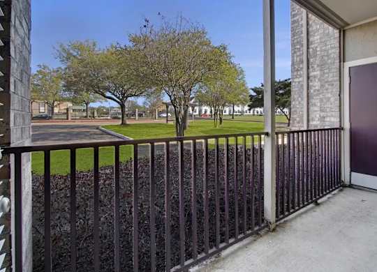 A view from a balcony looking out at a tree and a building.