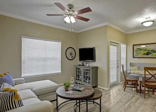 A living room with a sofa, a coffee table, a television, and a painting on the wall.