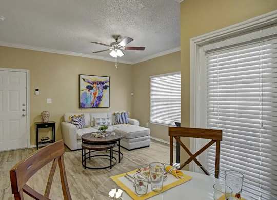 A living room with a white couch, a coffee table, and a painting on the wall.
