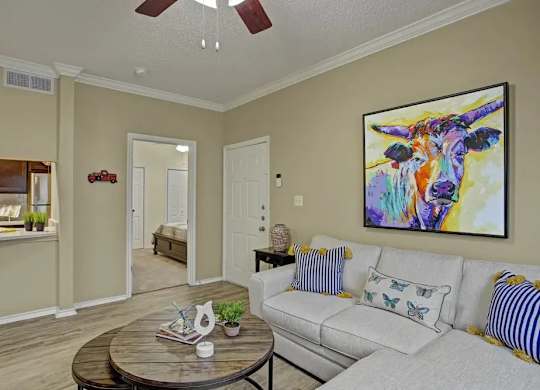 A living room with a white couch and a colorful painting on the wall.