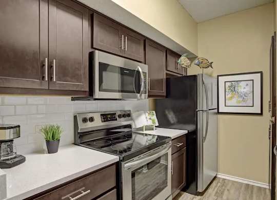 A kitchen with brown cabinets and a black refrigerator.