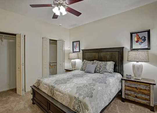 A bedroom with a large bed and a ceiling fan.