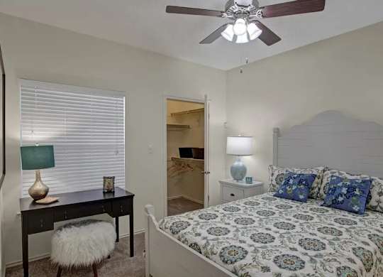 A bedroom with a bed, desk, and chair.