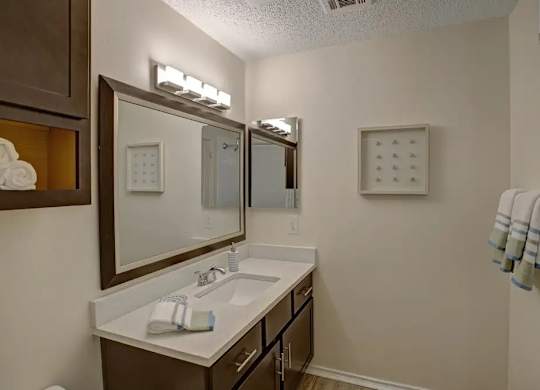 A bathroom with a sink, mirror, and towel rack.