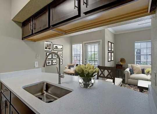 A kitchen with a sink and a countertop with a vase of flowers on it.