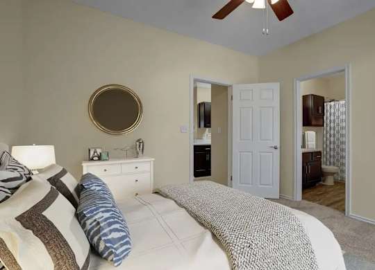 A bedroom with a bed, dresser, mirror, and a ceiling fan.