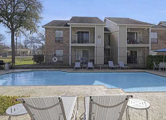 A pool in front of a building with a fence around it.