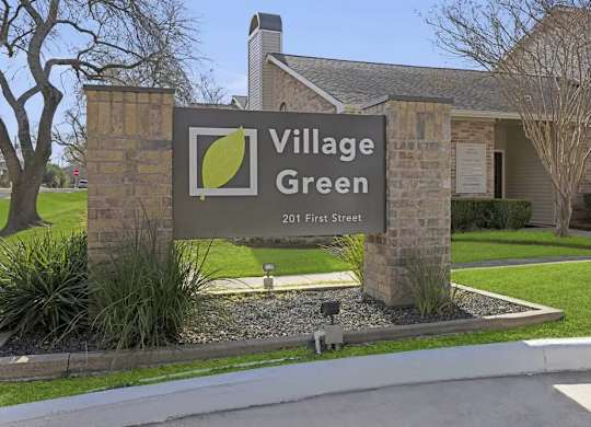 A sign for Village Green with a green leaf logo on it.