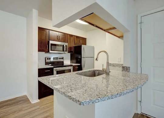 A kitchen with granite countertops and wooden cabinets.