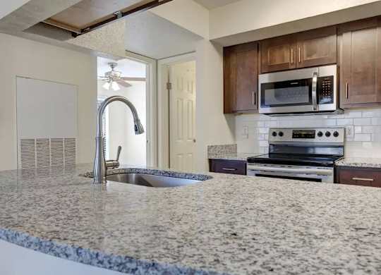 A kitchen with granite countertops and a stove top oven.