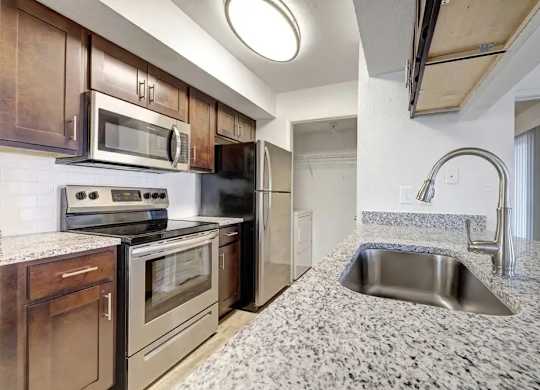 A kitchen with a granite countertop and stainless steel appliances.