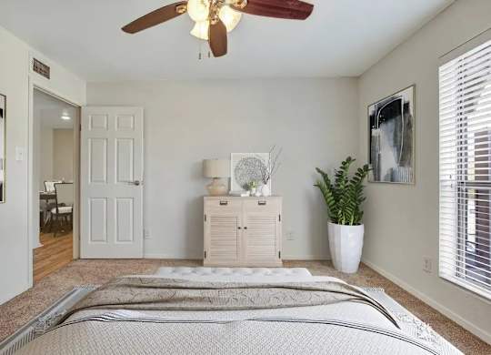 A bedroom with a bed, dresser, and ceiling fan.