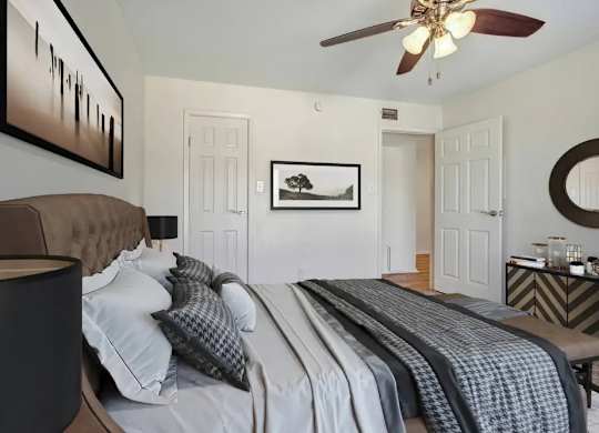 A bedroom with a large bed and a ceiling fan.